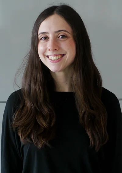 A woman with long brown hair wearing a black shirt smiling at the camera
